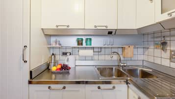 Una cocina con armarios blancos, electrodomésticos de acero inoxidable y un frutero sobre la encimera.