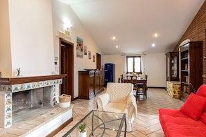 Un soggiorno con camino, zona pranzo e cucina sullo sfondo.