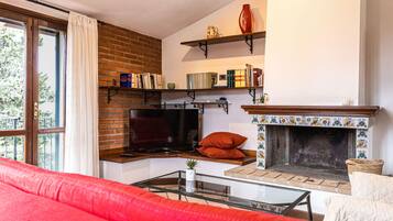 A cozy living room with a fireplace, bookshelves, and a red sofa.