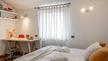 Un dormitorio con cama, escritorio y radiador.