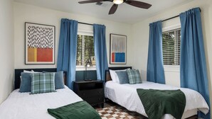 Ein Schlafzimmer mit zwei Betten, einem Deckenventilator und Kunstwerken an den Wänden.