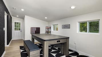 Una cocina moderna con una mesa de madera y un banco, un tapete a cuadrícula blanco y negro, una puerta con ventana y un estante en la pared con objetos.