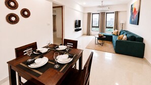 Uma sala de estar moderna com área de jantar, sofá e televisão.