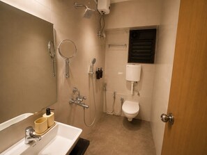 Et lille badeværelse med bruser, toilet og håndvask.