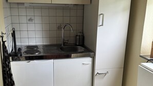 A compact kitchen with white cabinets, a stainless steel sink, and a tiled backsplash. - Cozy vacation home on two floors. Just 3 minutes to Lake Neukloster (Neukloster)