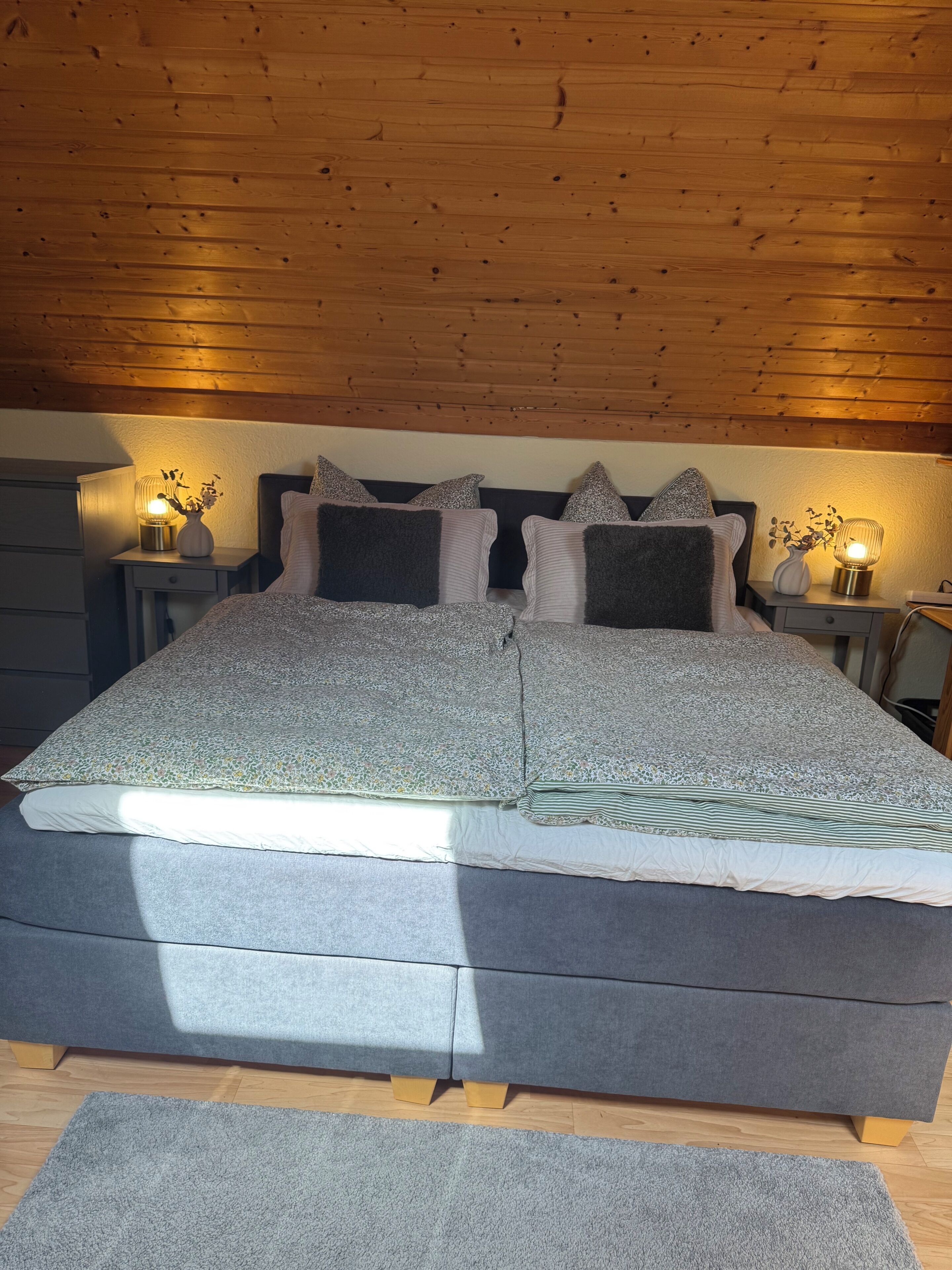 Een slaapkamer met een groot bed, twee nachtkastjes en een houten plafond.