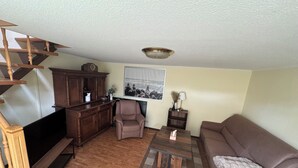 A living room with a wooden staircase, a sofa, a coffee table, and a television. - Cozy vacation home on two floors. Just 3 minutes to Lake Neukloster (Neukloster)