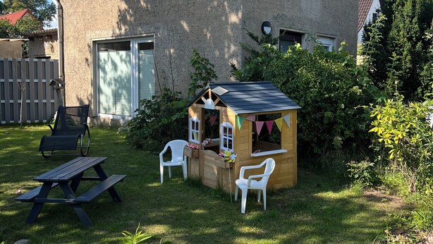 A house with a sloped roof, a satellite dish, a wooden playhouse, and a picnic table. - Cozy vacation home on two floors. Just 3 minutes to Lake Neukloster (Neukloster)