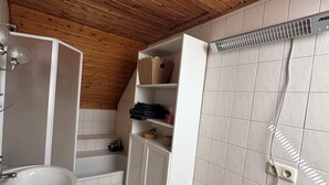 A bathroom with a wooden ceiling, white tiles, a sink, a cabinet, and a shower area. - Cozy vacation home on two floors. Just 3 minutes to Lake Neukloster (Neukloster)