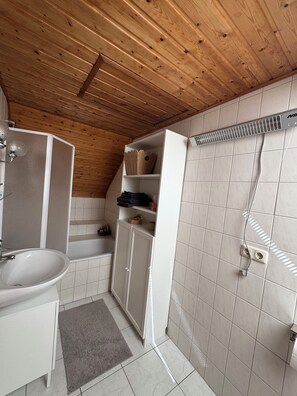 Un baño con techo de madera, azulejos blancos, un lavabo, un armario y zona de ducha.