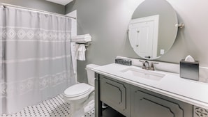 Une salle de bain avec un rideau de douche, des toilettes, un lavabo avec un miroir et un porte-serviettes.
