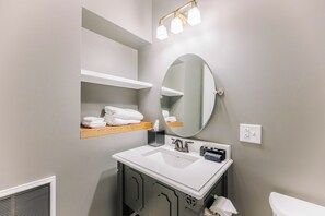 A bathroom with a white sink, a mirror, a towel rack, and a towel shelf. - Cozy Historic Inn Room by New River Trail (Max Meadows)