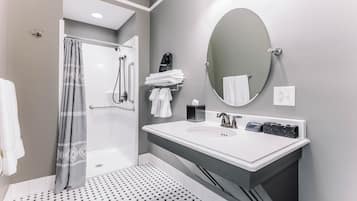 A modern bathroom with a shower, a sink with a mirror, and a towel rack.