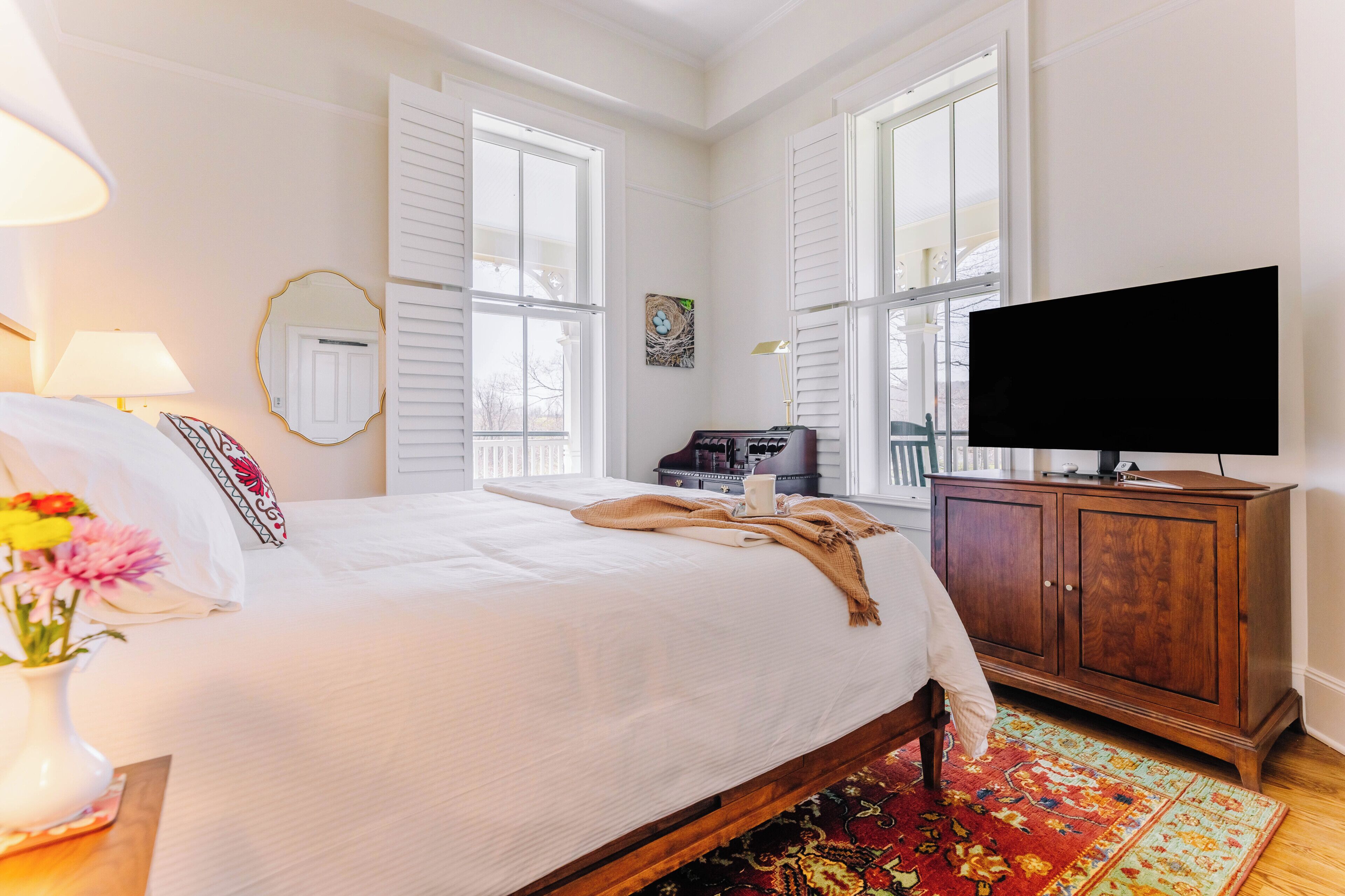 A bedroom with a bed, a television, a wooden cabinet, and a window.