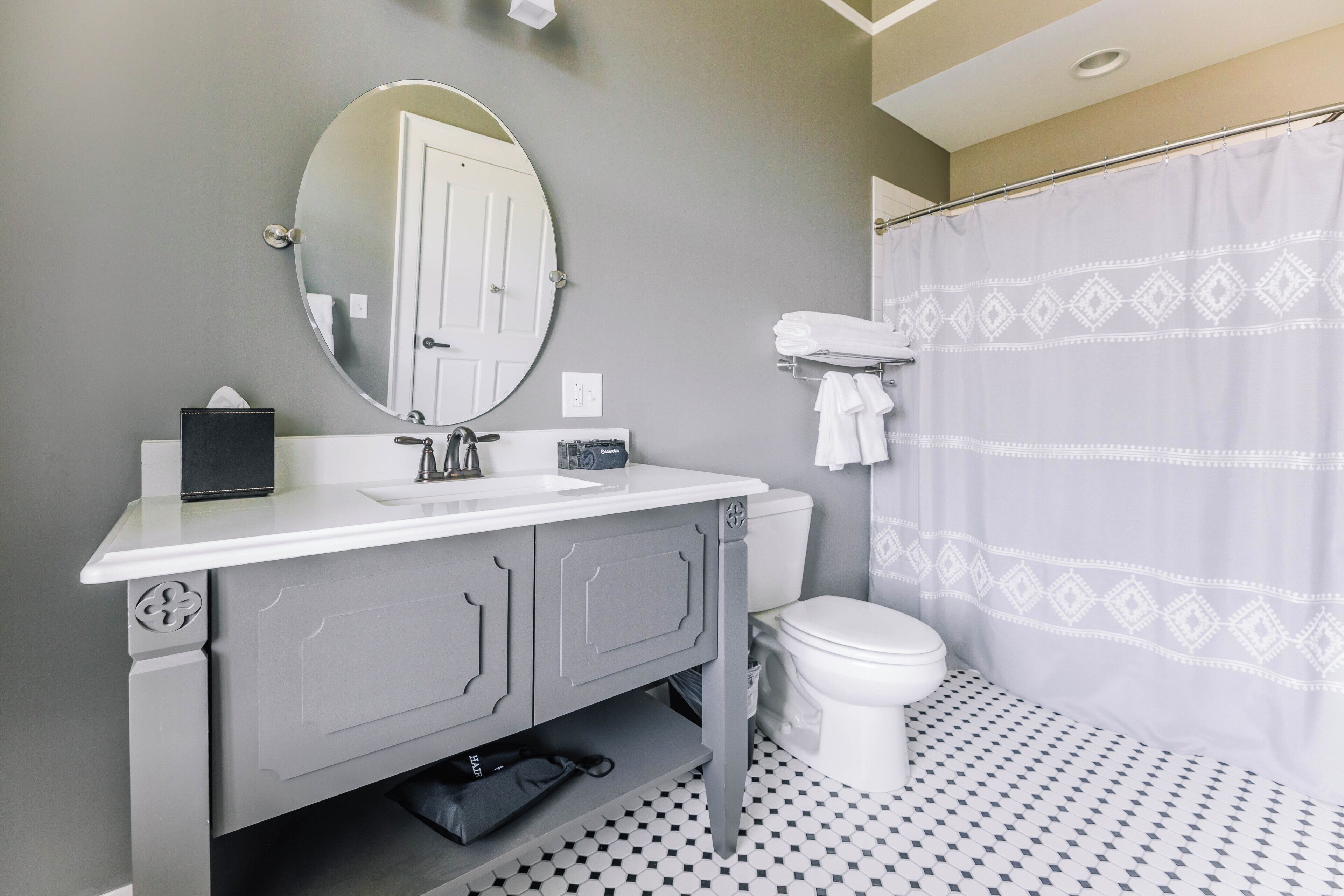 A bathroom with a white sink, a mirror, a toilet, and a shower curtain.