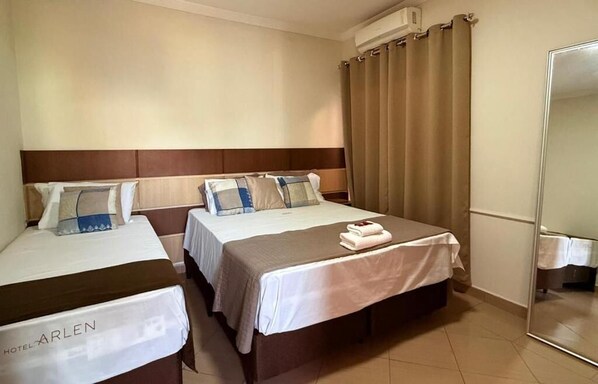Habitación de hotel con dos camas, un espejo y una cortina.