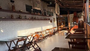 Ein Café-Interieur mit Holztischen und -stühlen, einem Fliesenboden und Regalen mit Küchenutensilien.