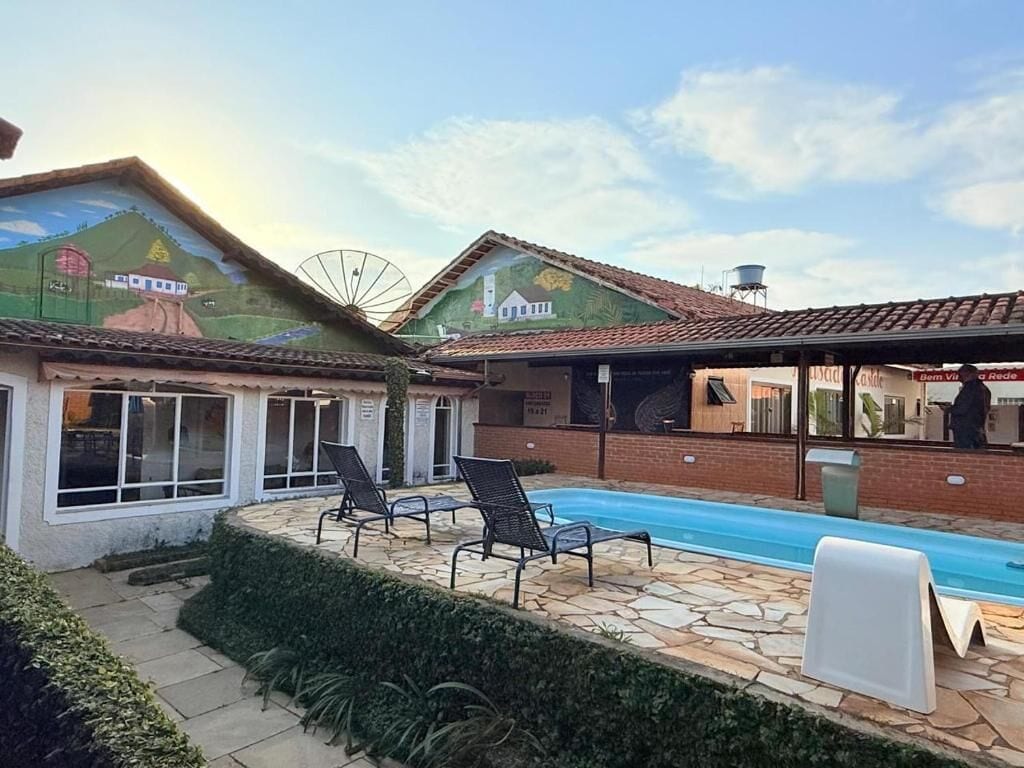 Propiedad residencial con piscina, mobiliario exterior y un mural en la fachada.