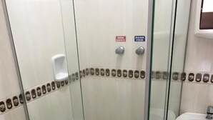 Ein Duschbereich mit Glaswänden, Toilette und Waschbecken.