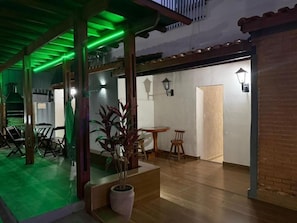 Un espacio interior con zona de comedor, planta en maceta y puerta que conduce a otra habitación.