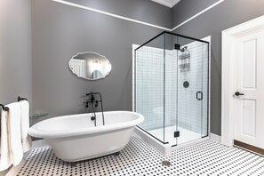 A bathroom with a freestanding bathtub, a glass-enclosed shower, and a white door. - Historic Honeymoon King Suite by New River Trail (Max Meadows)