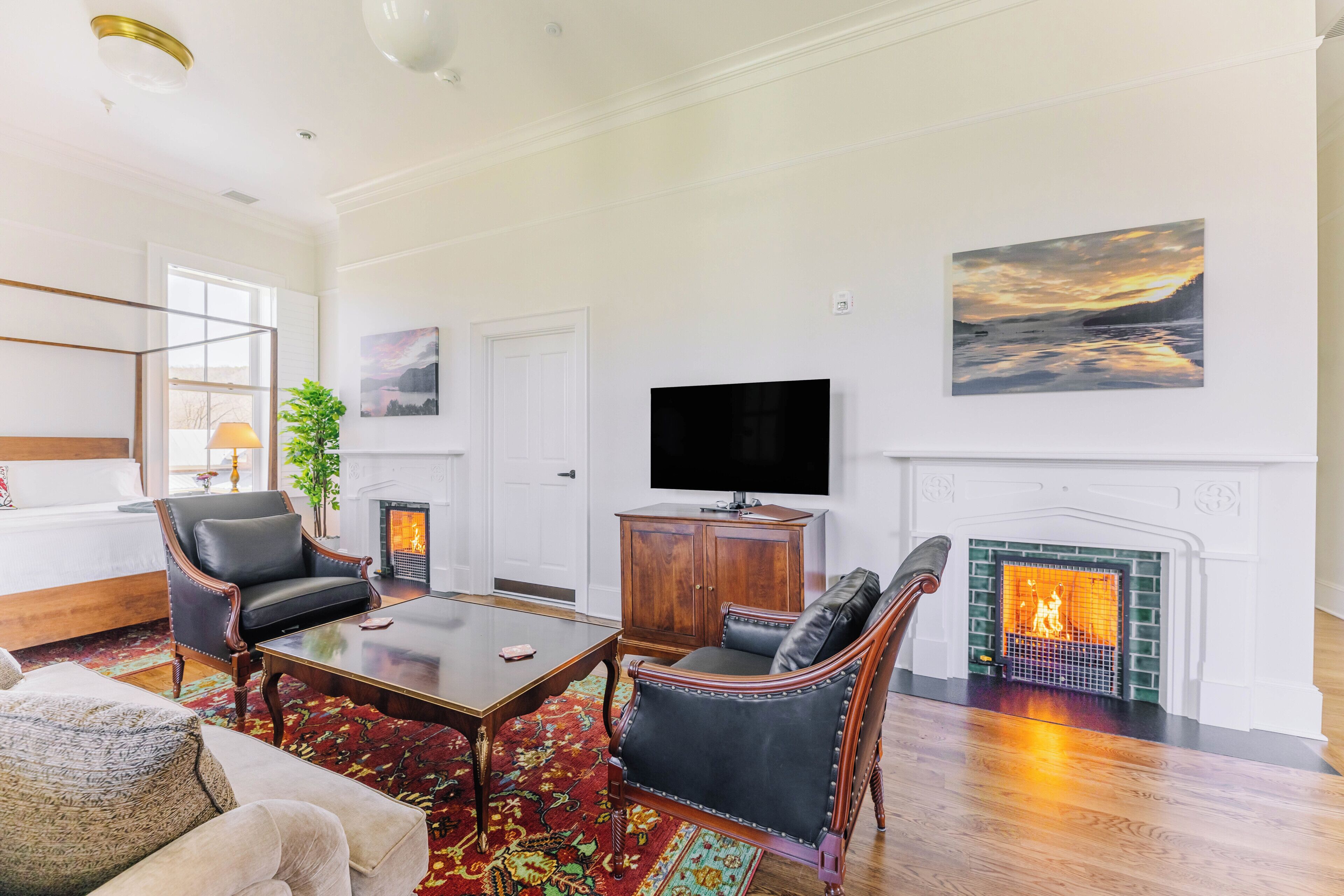 A spacious living room with a fireplace, a television, and a large painting on the wall.