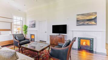A spacious living room with a fireplace, a television, and a large painting on the wall.