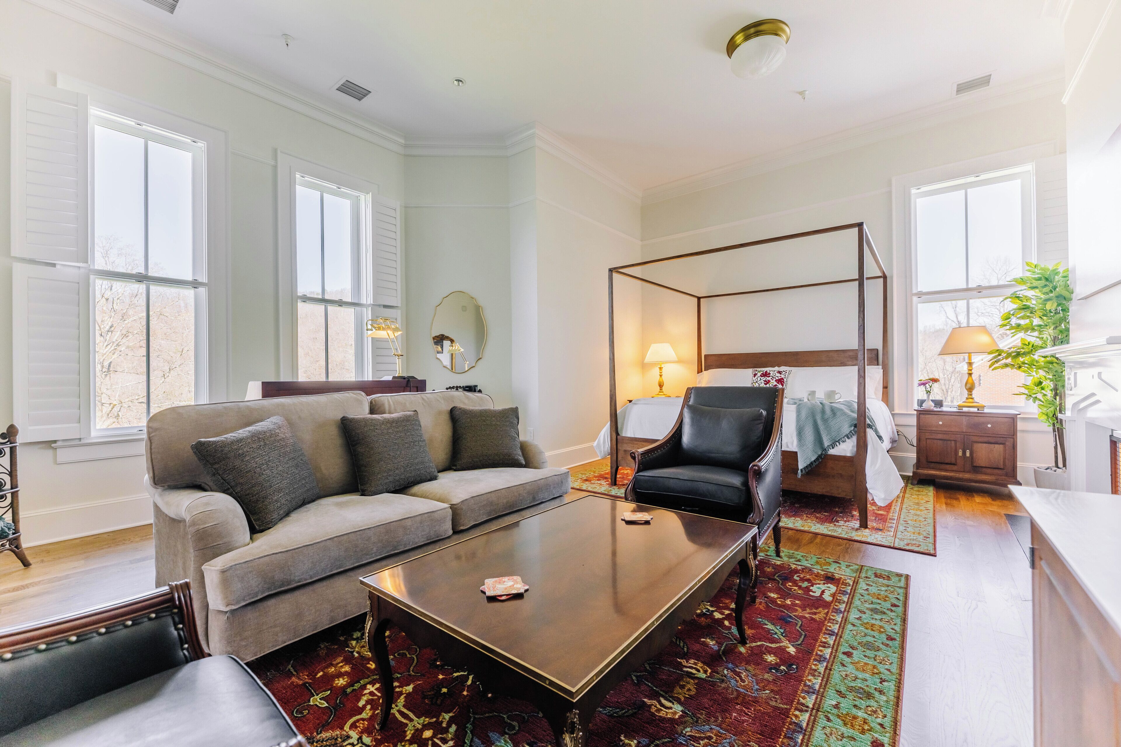 A spacious living room with a large sofa, a coffee table, and a four-poster bed.
