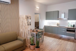 Eine moderne Küche mit grauen Schränken, einem Esstisch mit Stühlen und einer Couch im Wohnbereich.