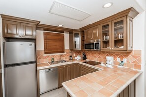 A kitchen with a refrigerator, microwave, sink, and cabinets.