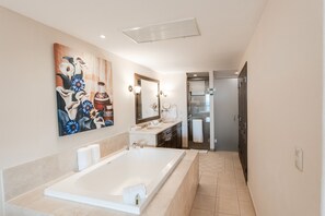 A modern bathroom with a large bathtub, a double sink, and a shower area.