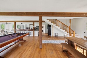 A spacious living area with a pool table, wooden flooring, a staircase, and a view of the kitchen and dining area. - 5-acre Historic Home With Pool Fishing Pond Game Room Outdoor Bar (Augusta)