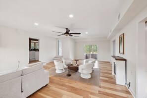 A spacious living area with a ceiling fan, a dining table with chairs, and a kitchen visible through an open door. - 5-acre Historic Home With Pool Fishing Pond Game Room Outdoor Bar (Augusta)