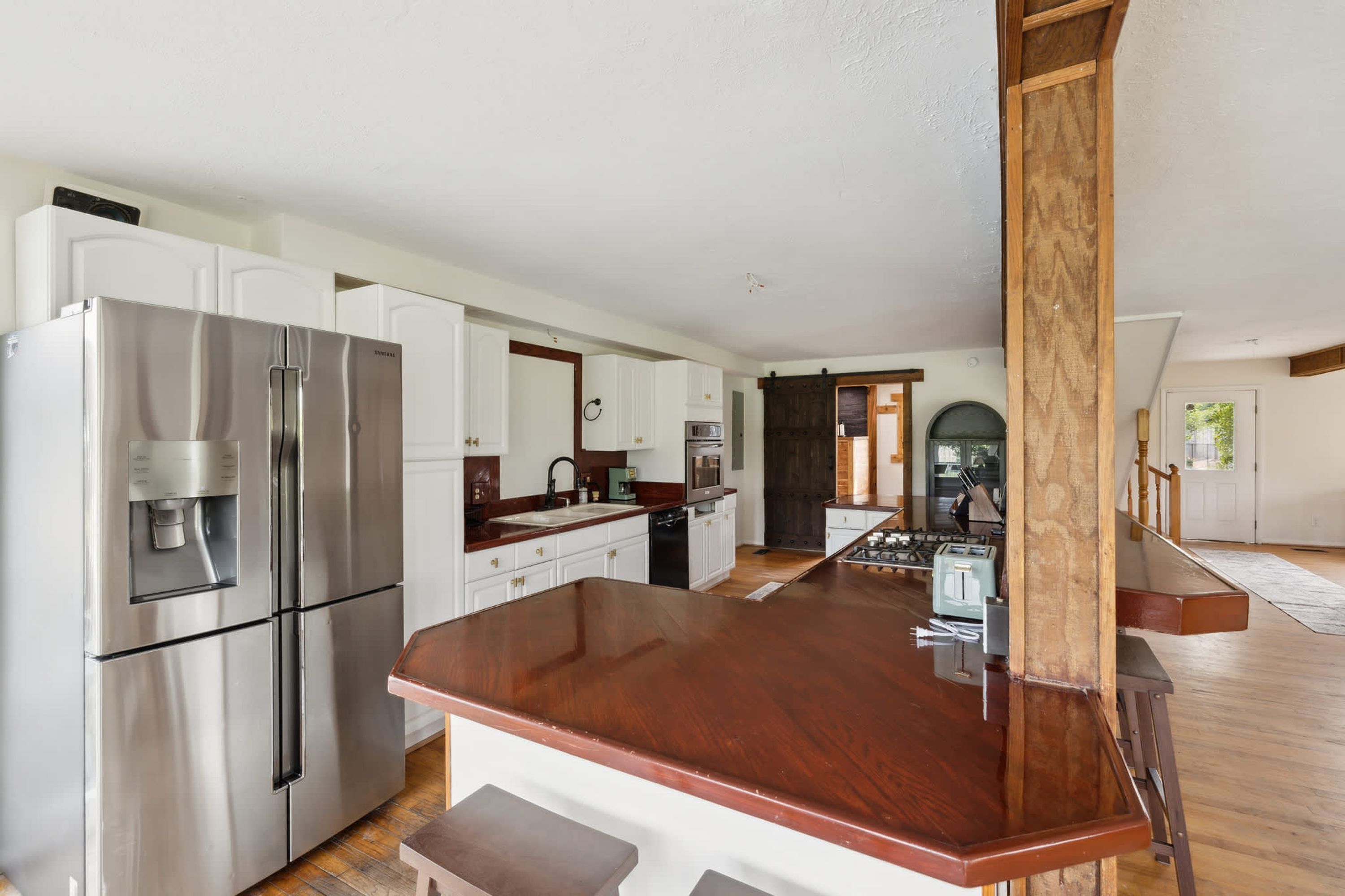 Een moderne keuken met roestvrijstalen apparatuur, witte kasten en een houten eiland.