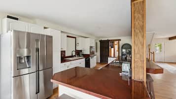 Een moderne keuken met roestvrijstalen apparatuur, witte kasten en een houten eiland.