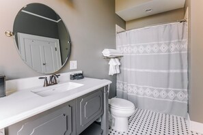 Een badkamer met een wit wastafel, een spiegel, een toilet en een douchegordijn.