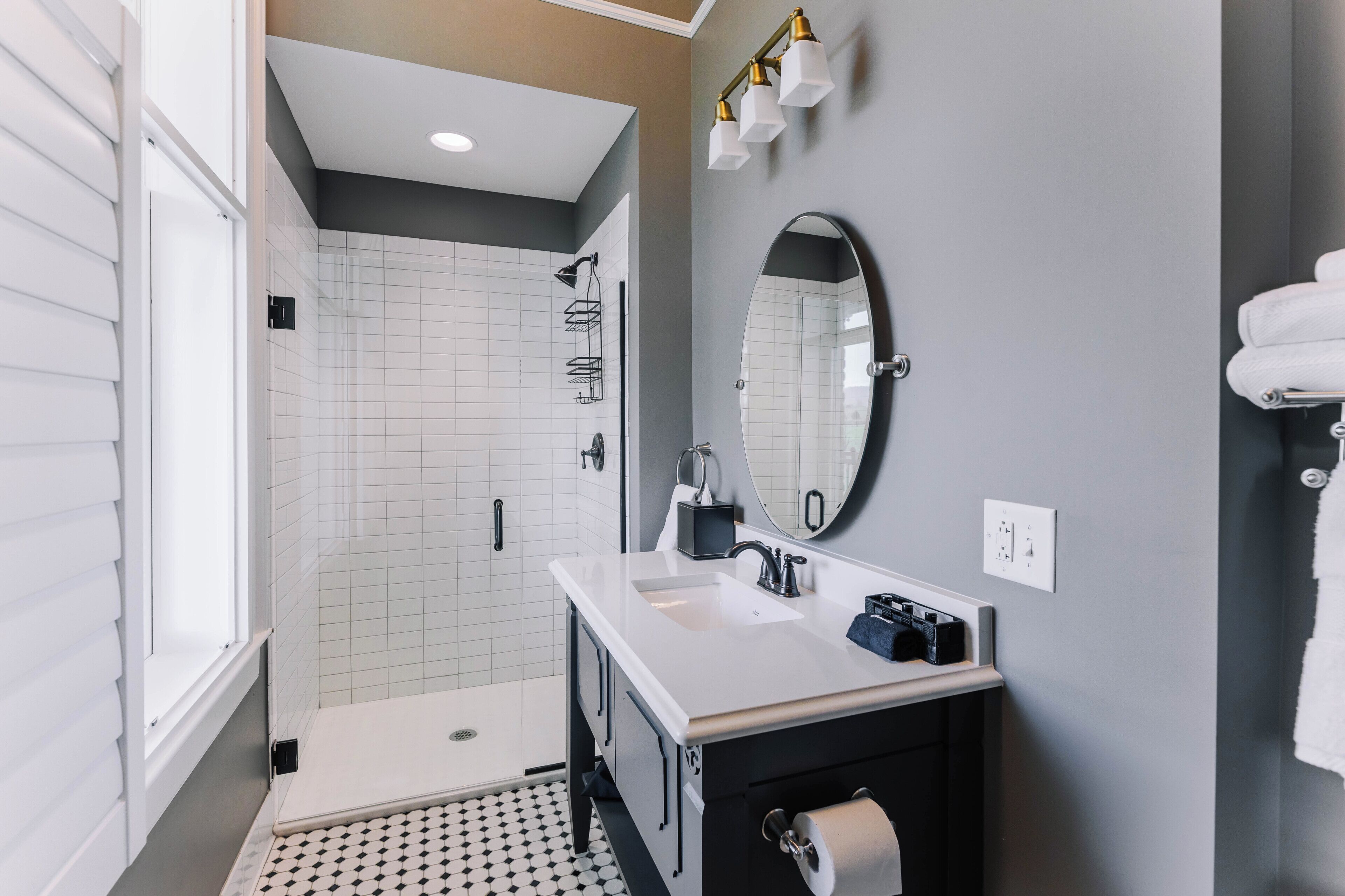 A modern bathroom with a shower, a sink, a mirror, and a toilet.
