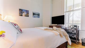 A hotel room with a bed, a TV, a coffee machine, and artwork on the wall.