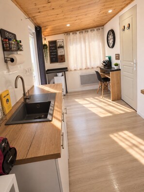 Une cuisine moderne équipée d’un évier, d’un plan de travail en bois et d’un coin repas avec une chaise.