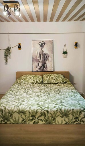 A bedroom with a bed, a painting on the wall, and a ceiling with wooden slats. - 7min Futuroscope - Havre de paix familial (Jaunay-Clan)