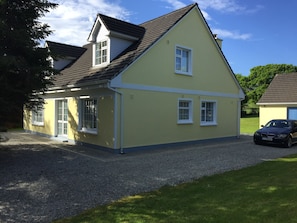A two-story house with a gravel driveway and a car parked in the driveway.