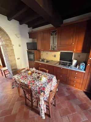 A kitchen with wooden cabinets, a tiled backsplash, a gas stove, and a dining table with chairs.