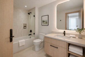 Ein modernes Badezimmer mit Badewanne, Toilette und Waschtisch mit Spiegel.