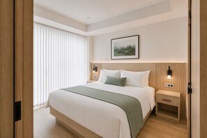 Ein Hotelzimmer mit einem großen Bett, Nachttischen, einer Wandlampe und einem Fenster mit Jalousien.