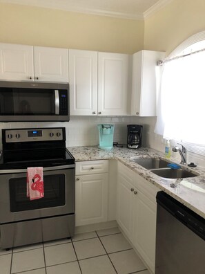 A kitchen with white cabinets, a microwave, an oven, a coffee maker, and a dishwasher. - Adorable 2-bedroom condo with AC in Myrtle Beach. First floor condo (Myrtle Beach)