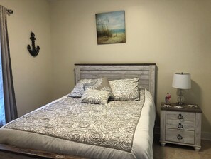 A bed with patterned bedding, a nightstand with a lamp, and a painting on the wall. - Adorable 2-bedroom condo with AC in Myrtle Beach. First floor condo (Myrtle Beach)