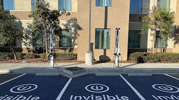 A parking area with electric vehicle charging stations and 'Invisible Urban' painted on the ground.