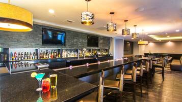 A bar area with a long counter, multiple seating options, and a television mounted on the wall.