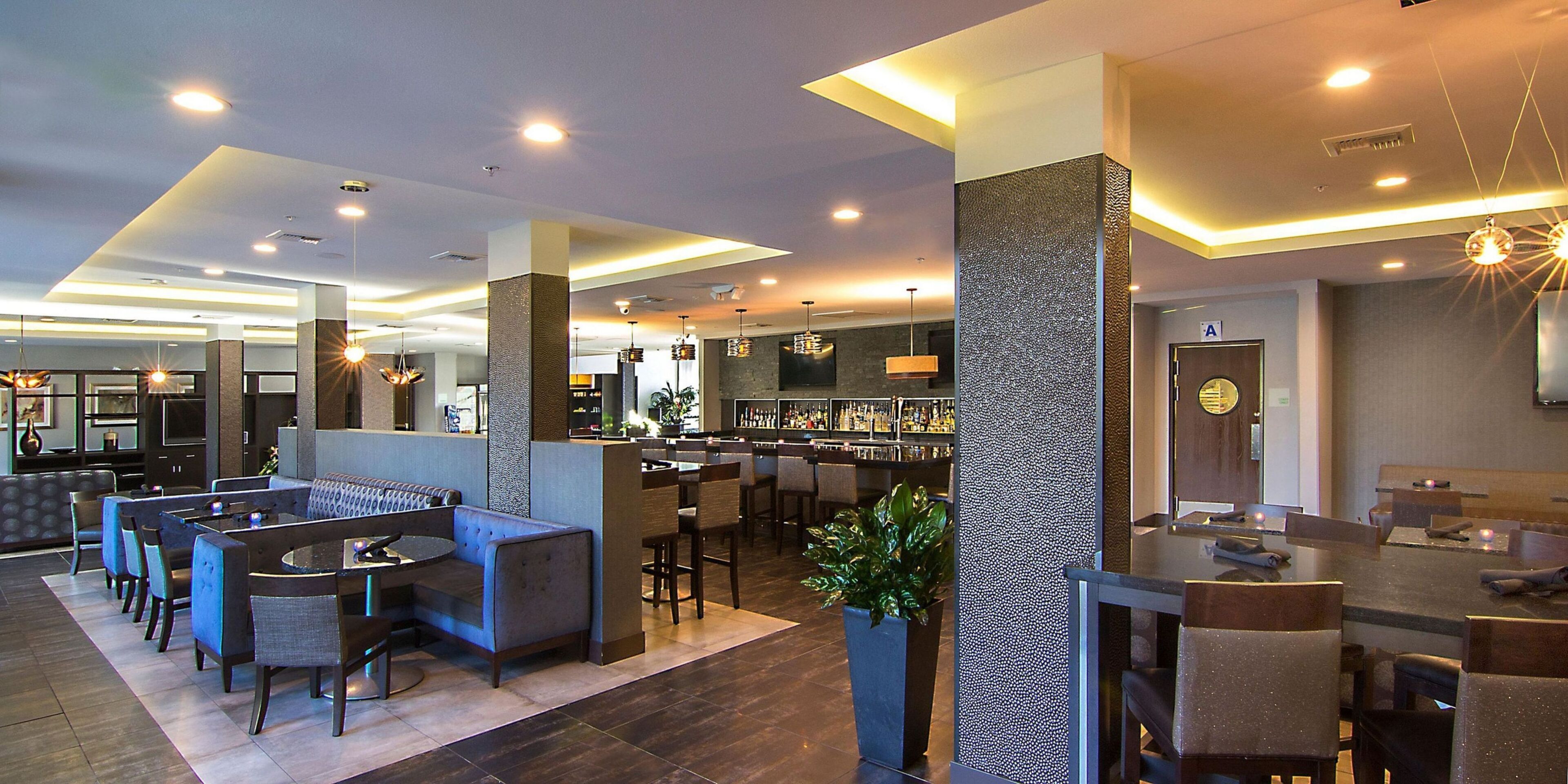 A modern hotel lobby with a bar area, seating arrangements, and a reception desk.