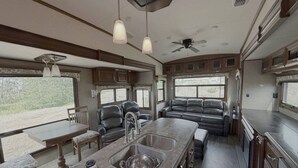 Una cocina con una isla central, dos lámparas colgantes y un ventilador de techo.